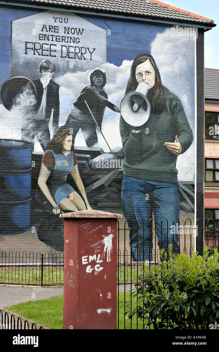 Graffiti and Art: A graffiti covered gate post in front of a graphic bogside mural Bernadette The Battle of the Bogside Stock Photo