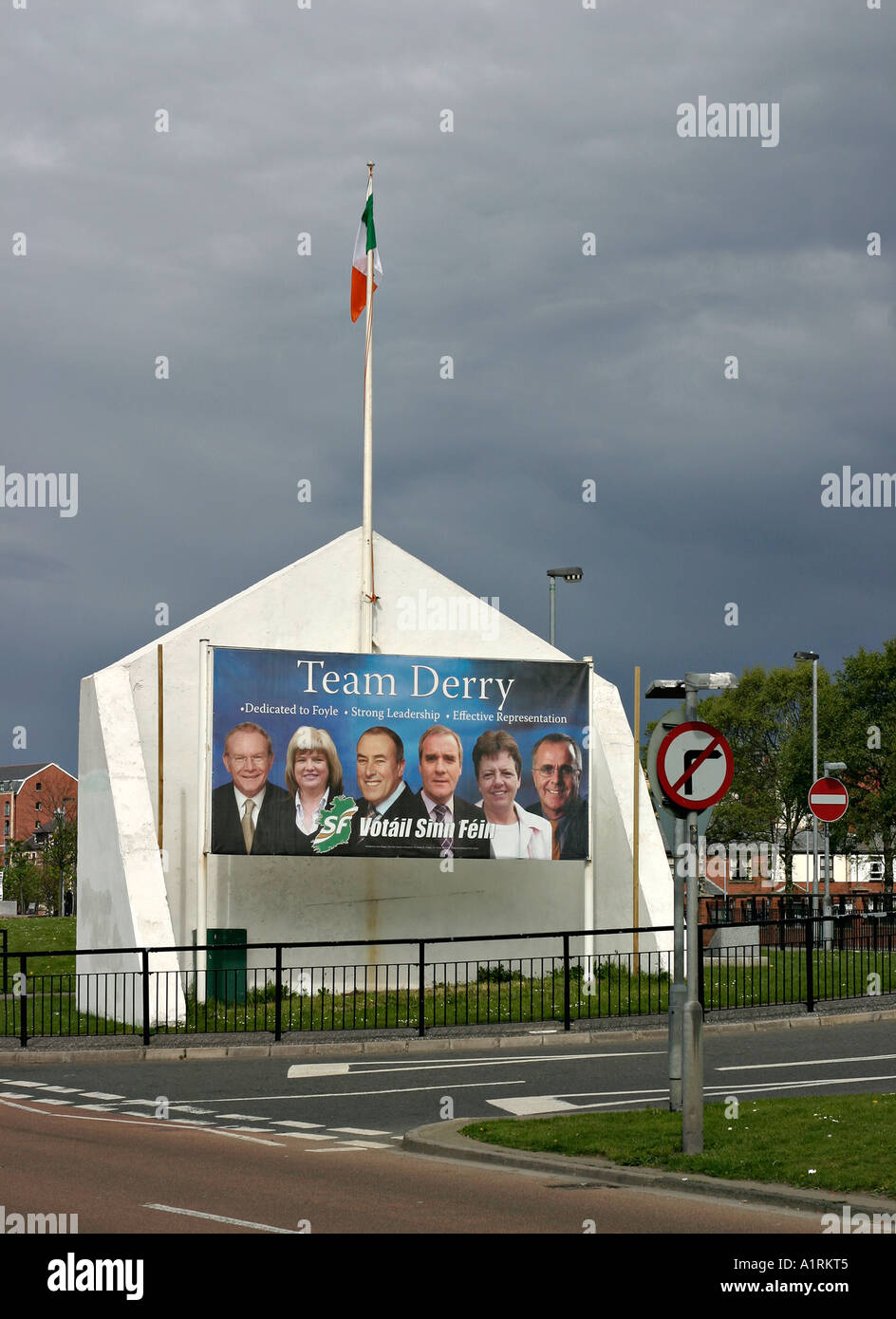 Election poster for Catholic Derry. A sun lit election Mural for Sinn Fein with an Irish republican flag flying overhead Stock Photo