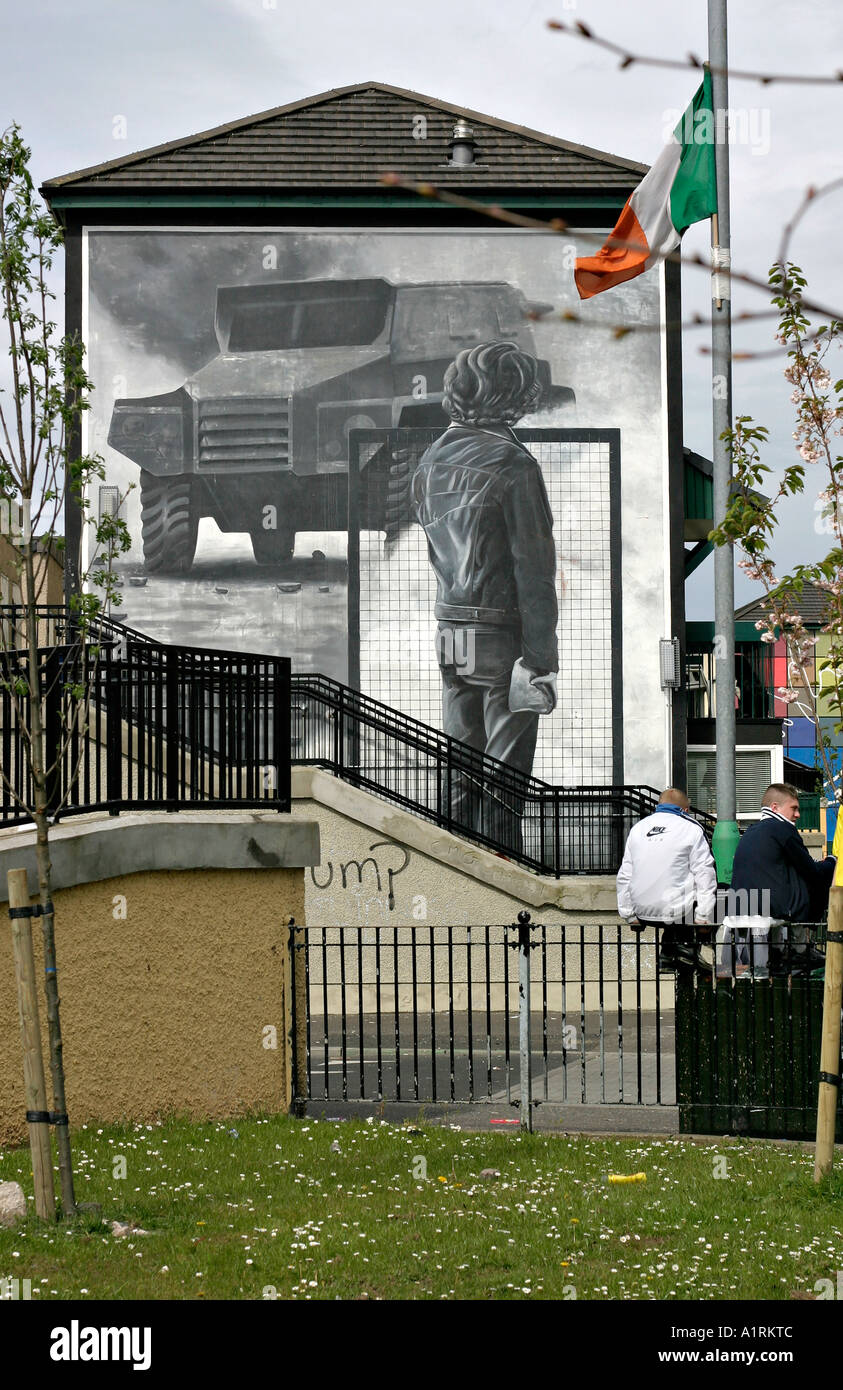 Waiting beside the Riot. A group of boys sits on a wall in front of the bogside mural The Rioter An irish republican flag flys Stock Photo