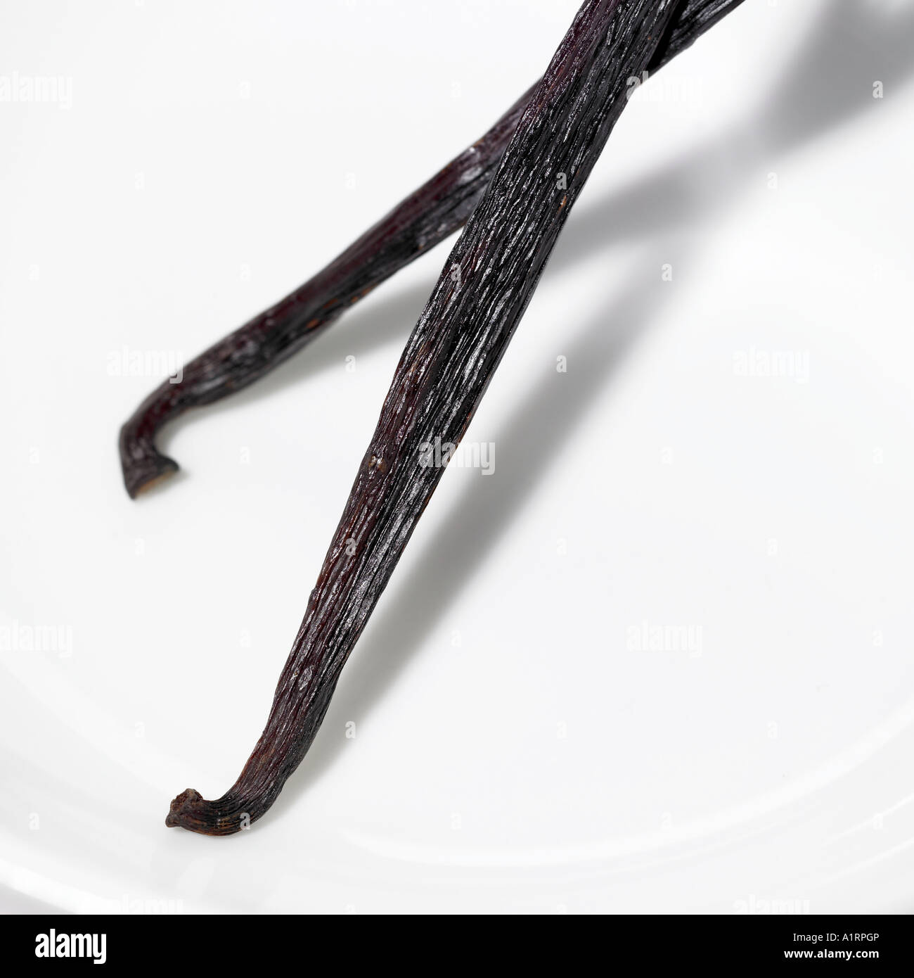 two vanilla pods overlapped on a white plate Stock Photo