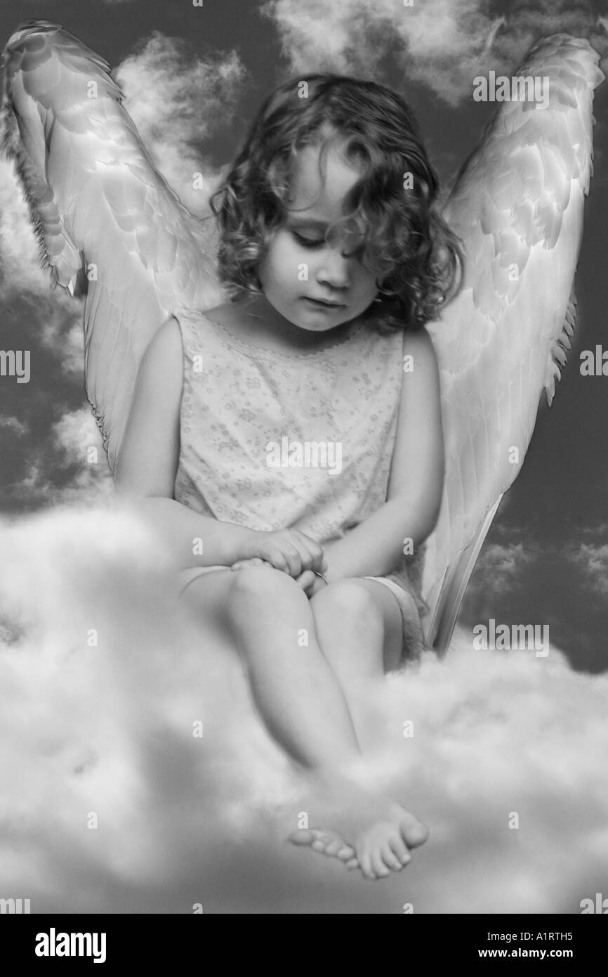 angel (infant) in a skirt seating on clouds like an angel (with wings) Stock Photo