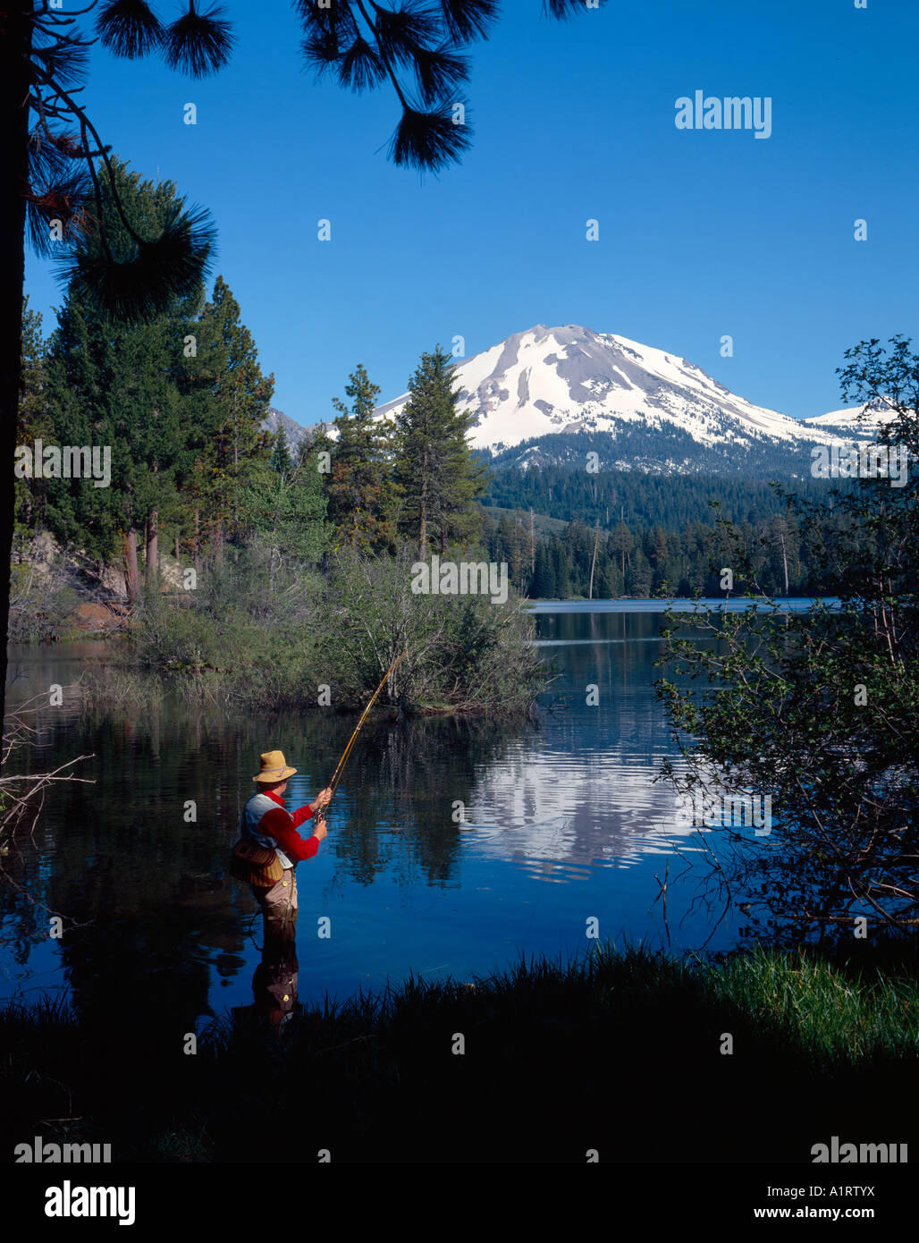 Fly fisherman in hip boot waders casting into the waters of Manzanita
