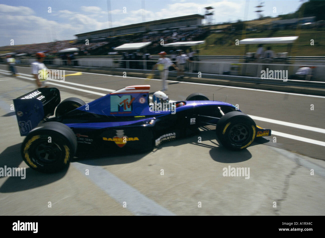 ELECTRIC BLUE RACE CAR AND DRIVER IN WHITE HELMET SIT ON TARMAC BY THE ...