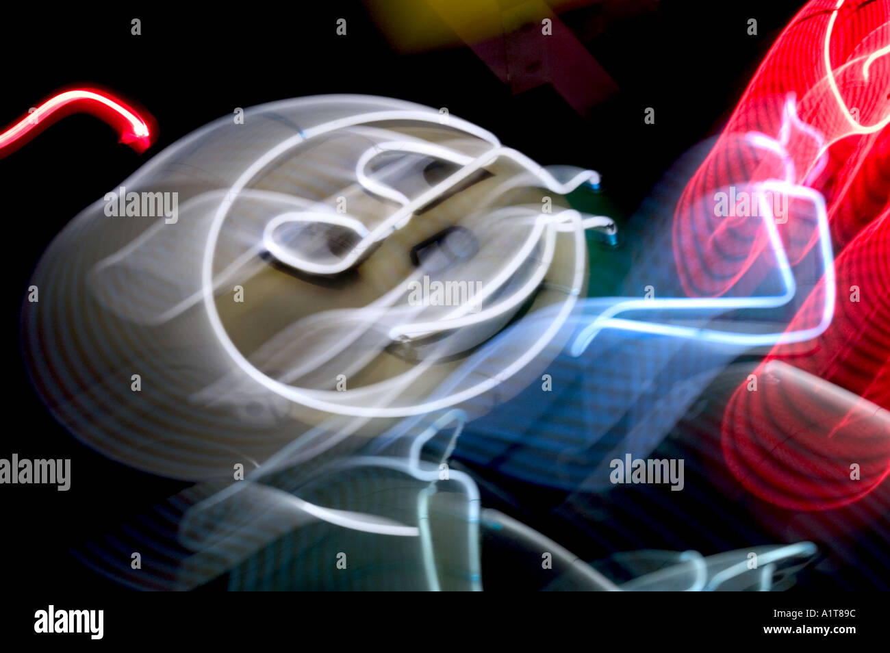 A blurred neon sign of a round headed man pointing with an antenna on its head Stock Photo