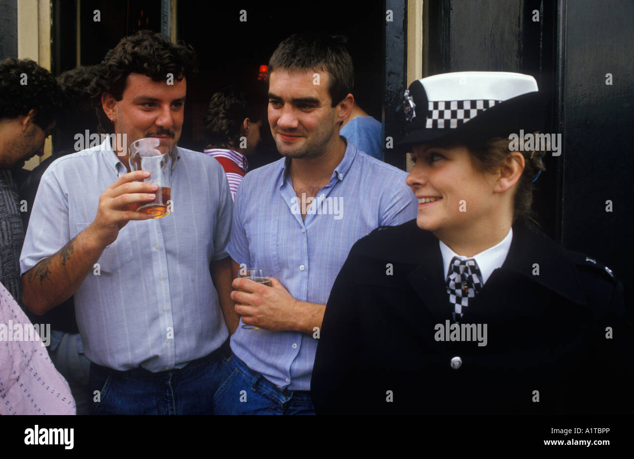 1980s Chelsea football club fans having a pint before the game flirting with an attractive female police woman on crowd control duty London UK 1985 Stock Photo