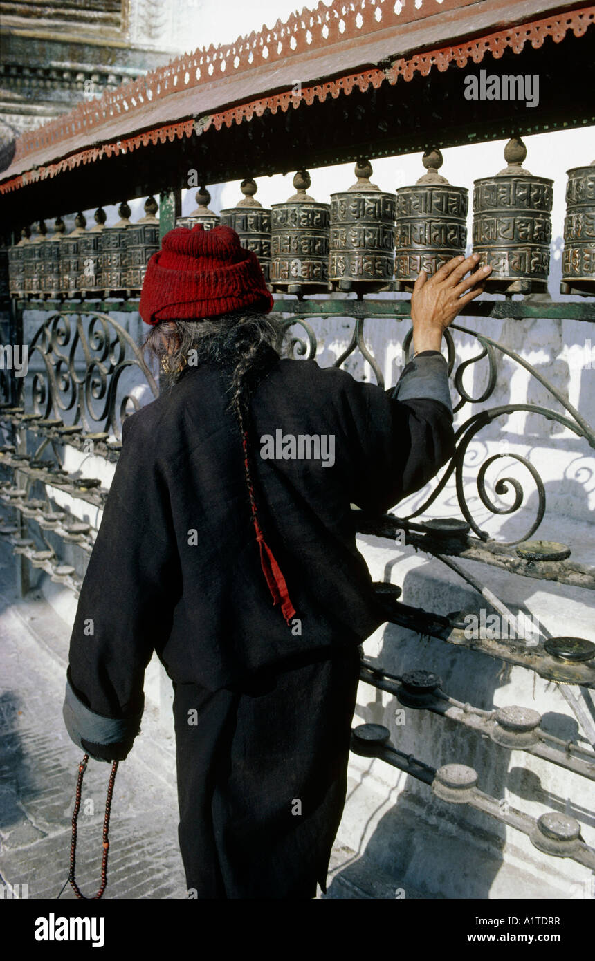 man at prayer rolls area of swayambunath temple near city of kathmandu nepal Stock Photo