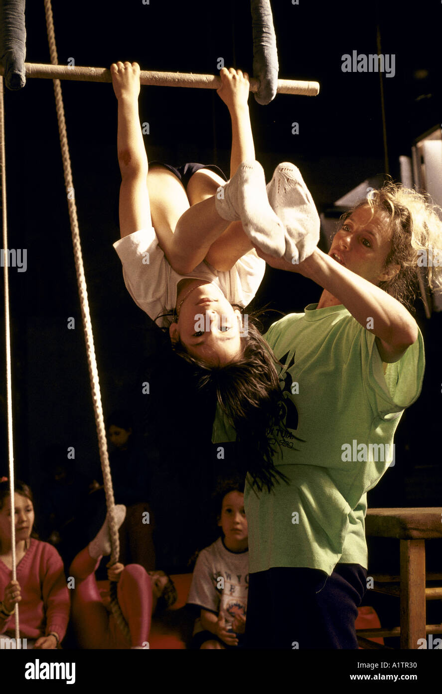 CIRCUS SCHOOL ISLINGTON. Young girl sits on training trapeze with teacher Stock Photo