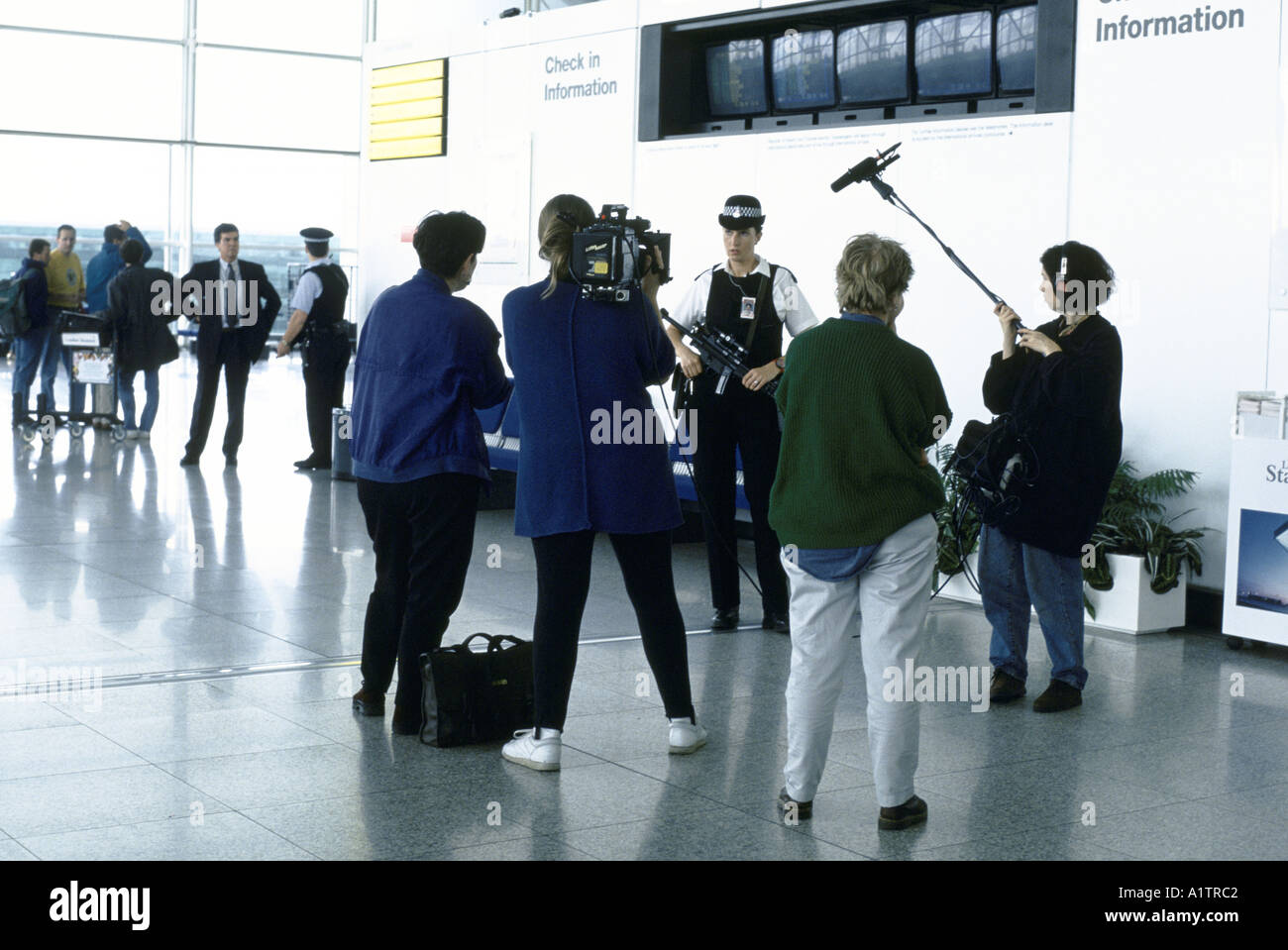 ARMED FEMALE POLICE OFFICER BEING INTERVIEWED BY TV CREW CACTUS FILMS STANSTEAD AIRPORT Stock Photo