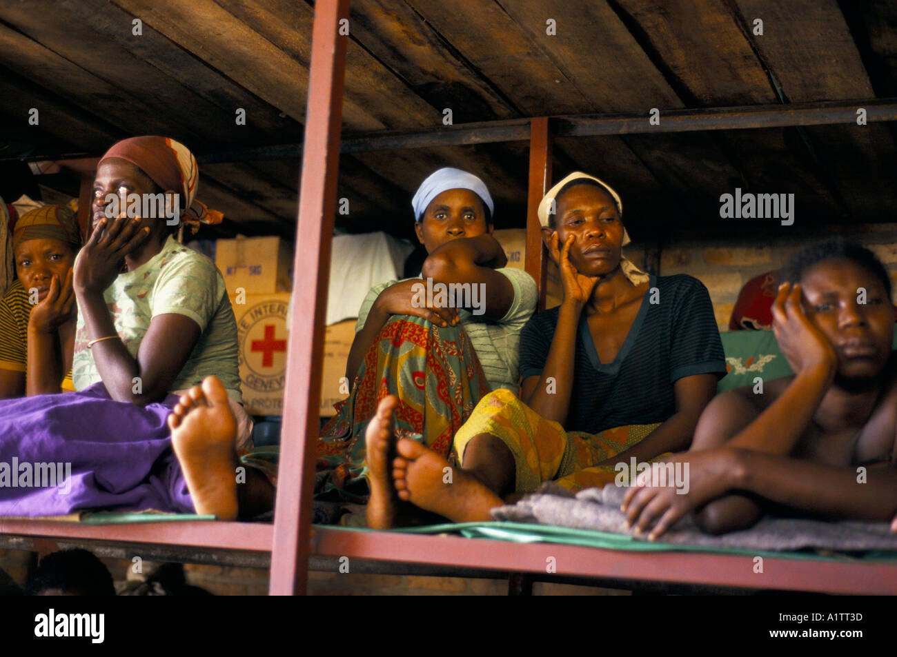 Prisoners accused of genocide.  WOMEN HOLDING THEIR HEADS SITTING LYING ON BEDS IN BUTARE PRISON 1995 Stock Photo