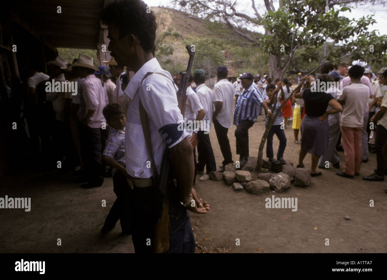 MAN WITH RIFLE GUARDING VOTERS QUEUEING TO VOTE IN NICARAGUAN ELECTIONS 1990 Stock Photo