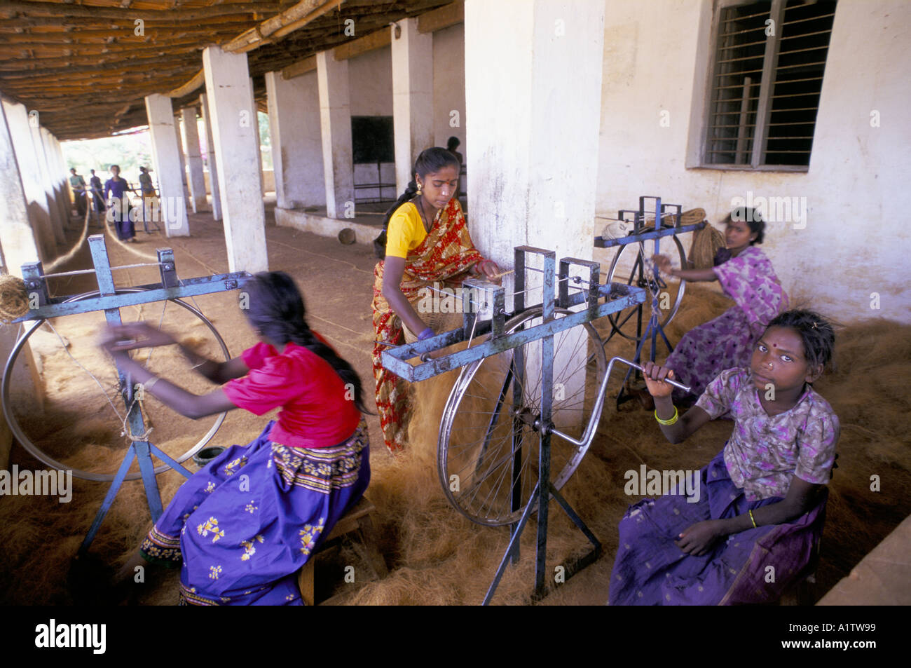 INDIA KARNATAKA. YOUNG WOMEN SPINNING COCONUT FIBRE FOR ROPE MAKING ...