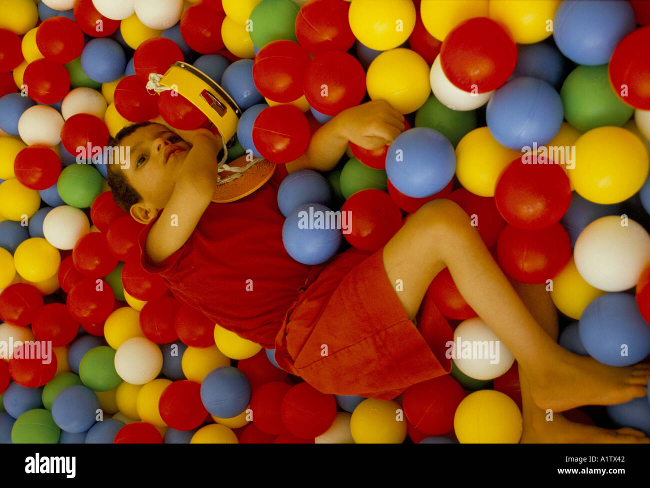 GIRL WITH CEREBRAL PALSY RELAXING ON A MASS OF BRIGHTLY COLOURED
