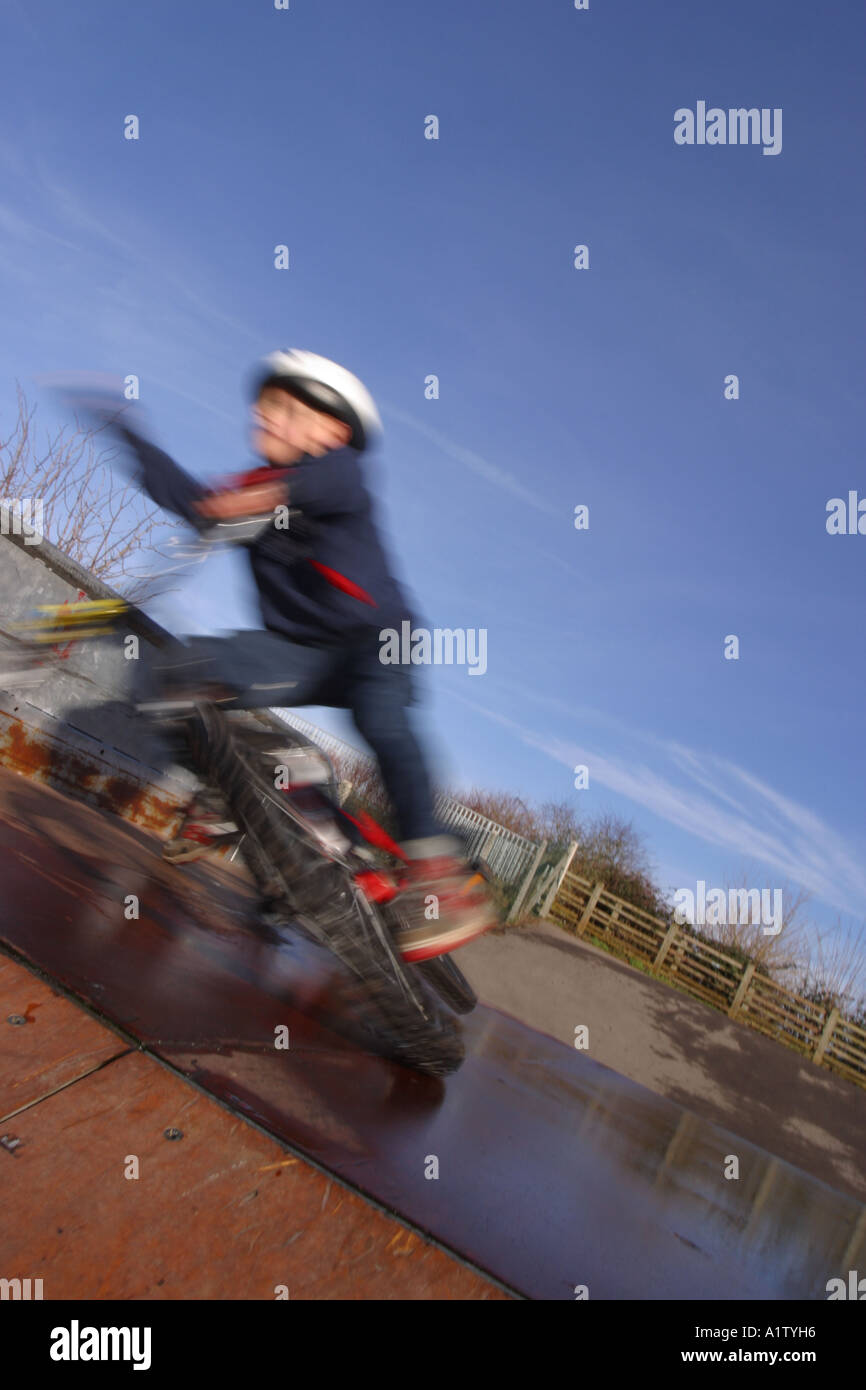 Accident Young child boy falling off a bicycle at BMX bike park on a wet ramp jump accident Stock Photo