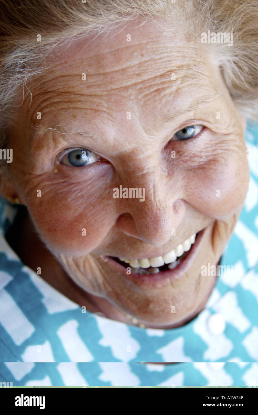 Model released close up portrait of a tanned nice elderly woman with blue eyes and a white and blue dress Stock Photo