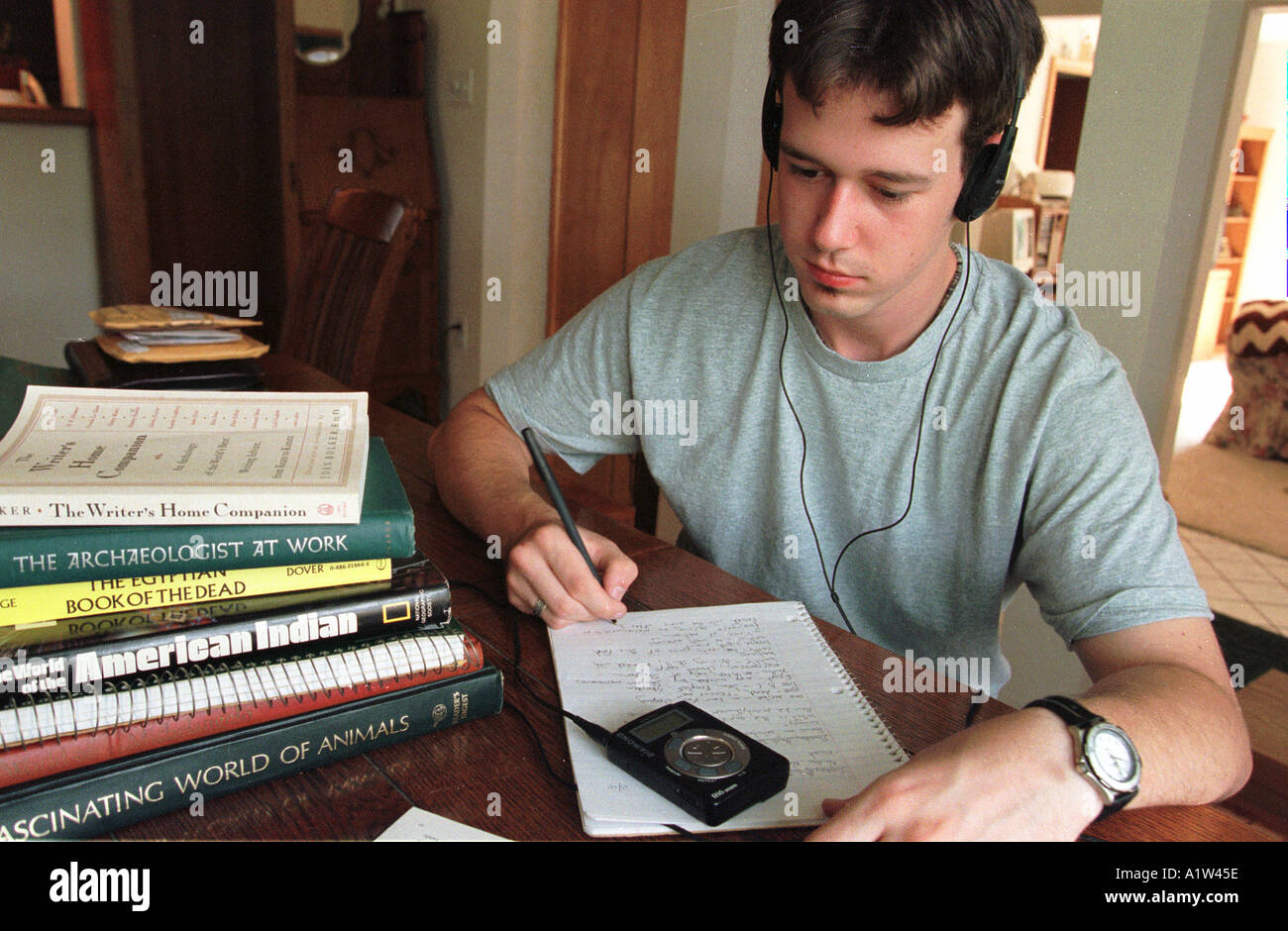 Student listens to music on his MP3 player while studying Stock Photo
