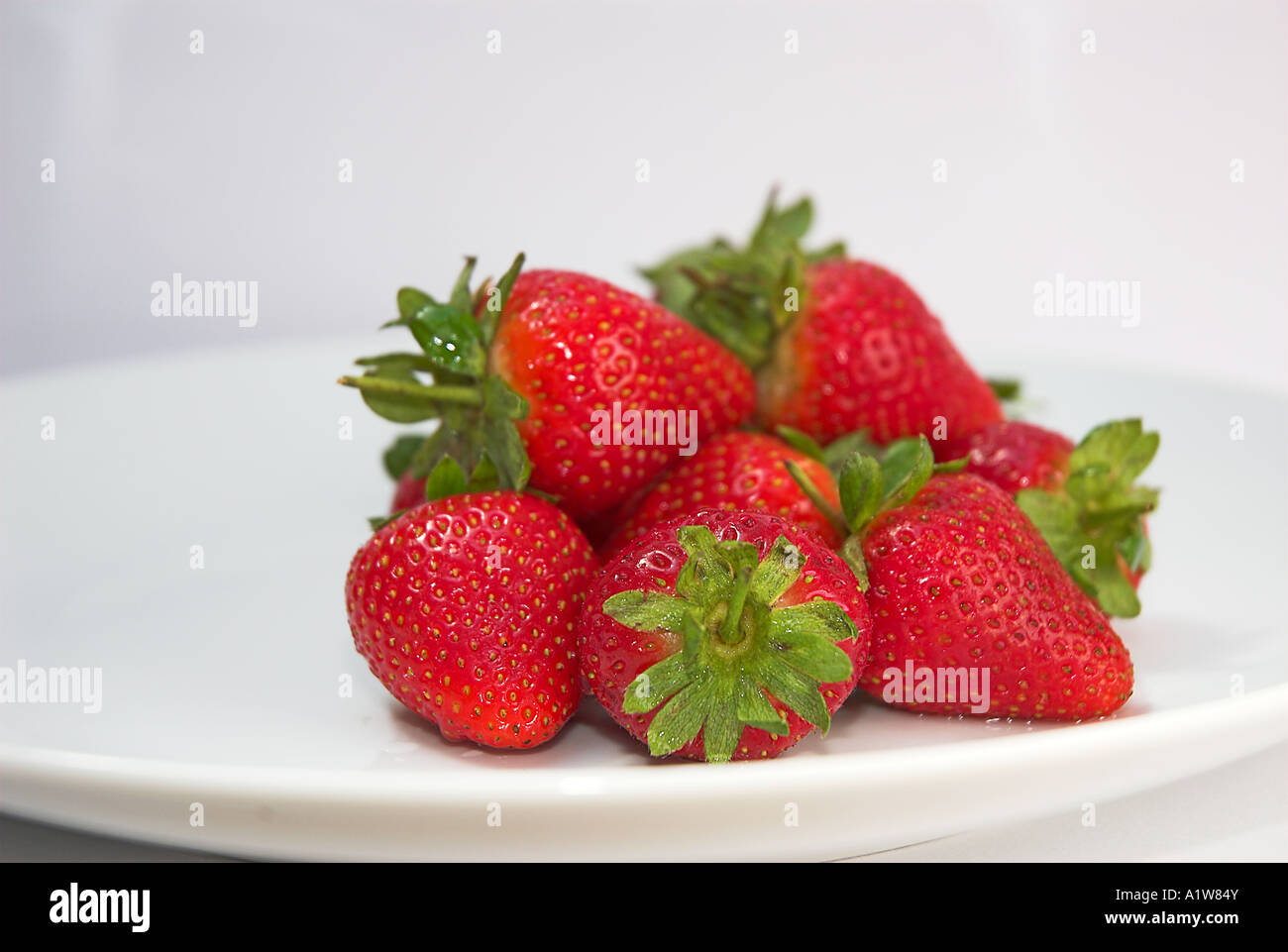 strawberries on a white plate with a white background Stock Photo - Alamy