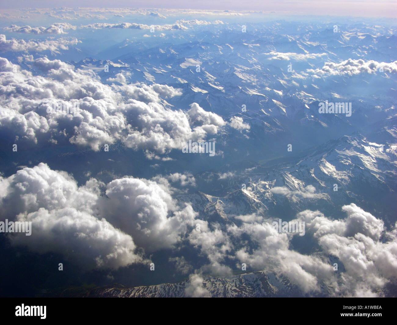 the alps high in the sky CLOUDS formations seen from above aloft out of a aircraft window fly over THE ALPES Stock Photo
