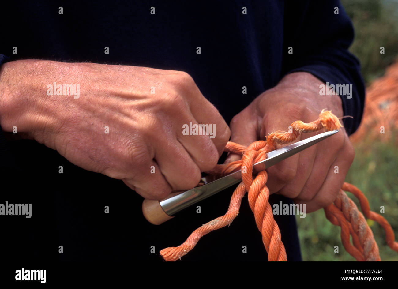Close up of a fishermans hands who is mending rope and net Stock Photo