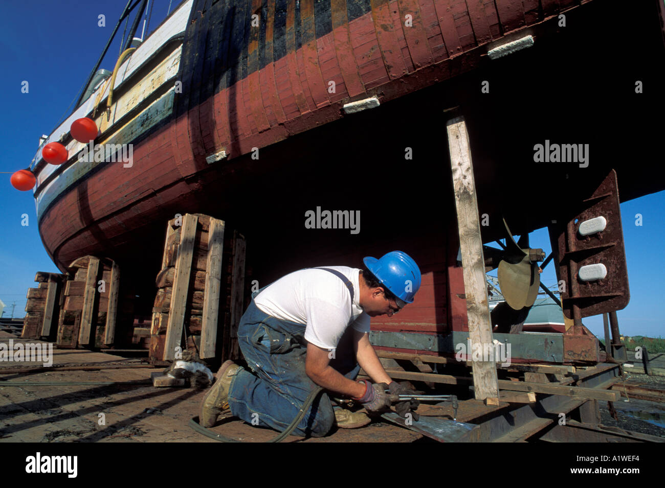 Welder working on a fishing boat in dry dock Nova Scotia Canada Stock Photo