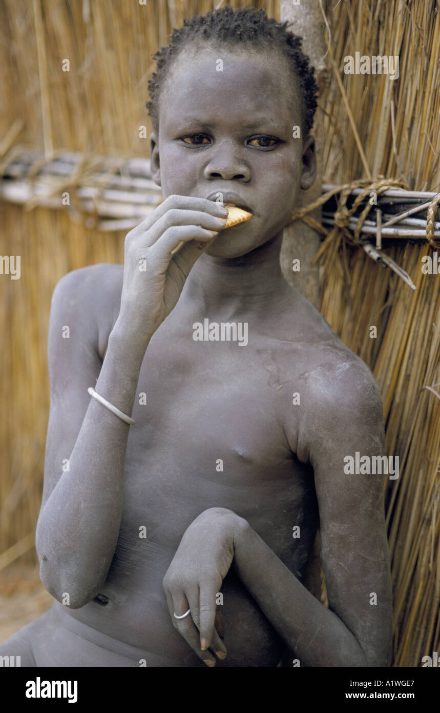 SOUTH SUDAN AUGUST 1998 YOUNG WOMAN EATING BISCUIT RATION DURING FAMINE IN AJIEP Stock Photo