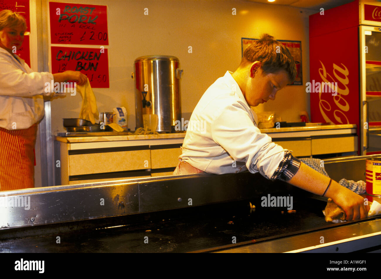 CHILD WORKING CLEANING HOTPLATE IN TRAILER SELLING FAST FOOD  BANBURY FUNFAIR Stock Photo