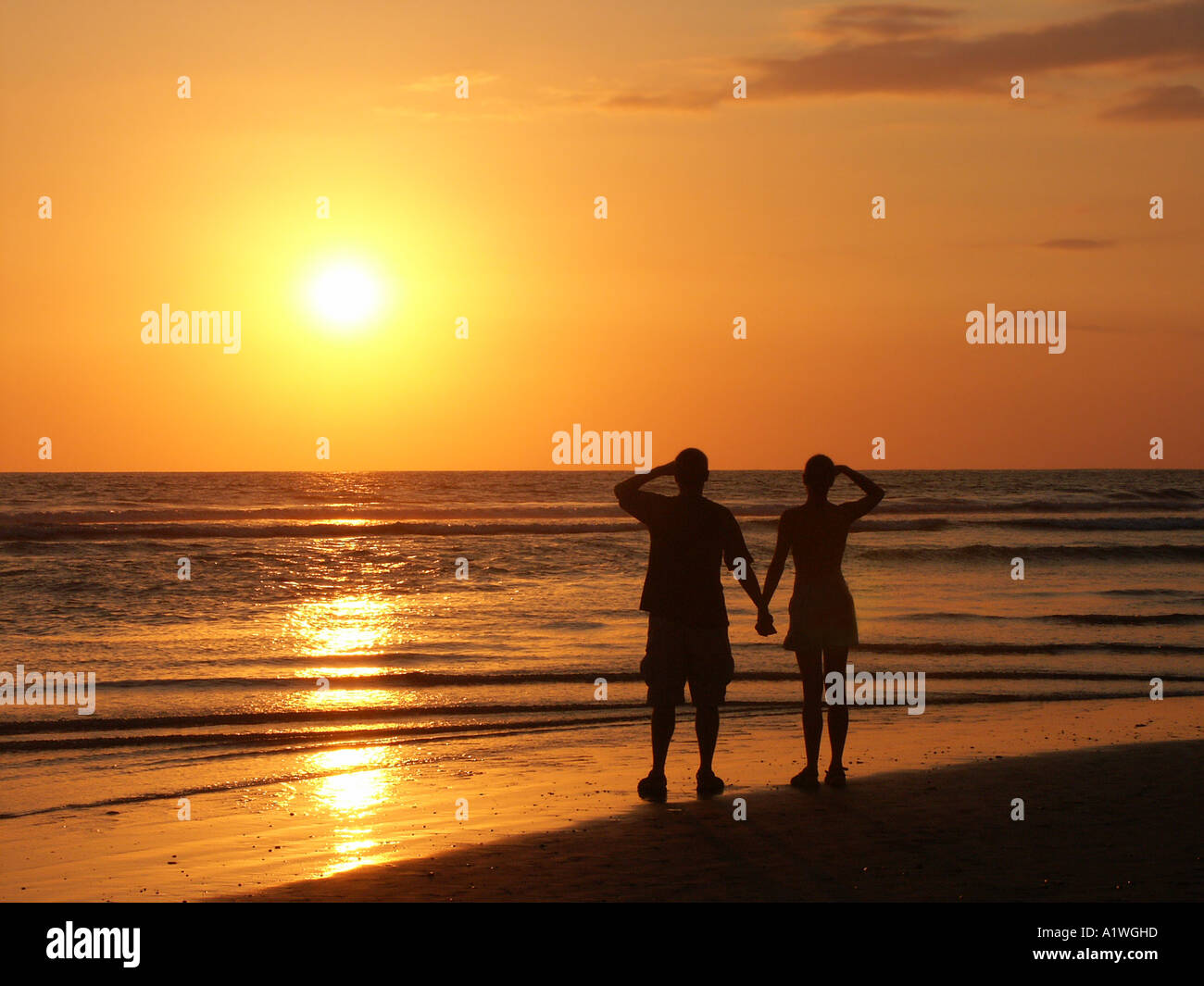 Young Couple Watching the Sunset on the Beach Stock Photo