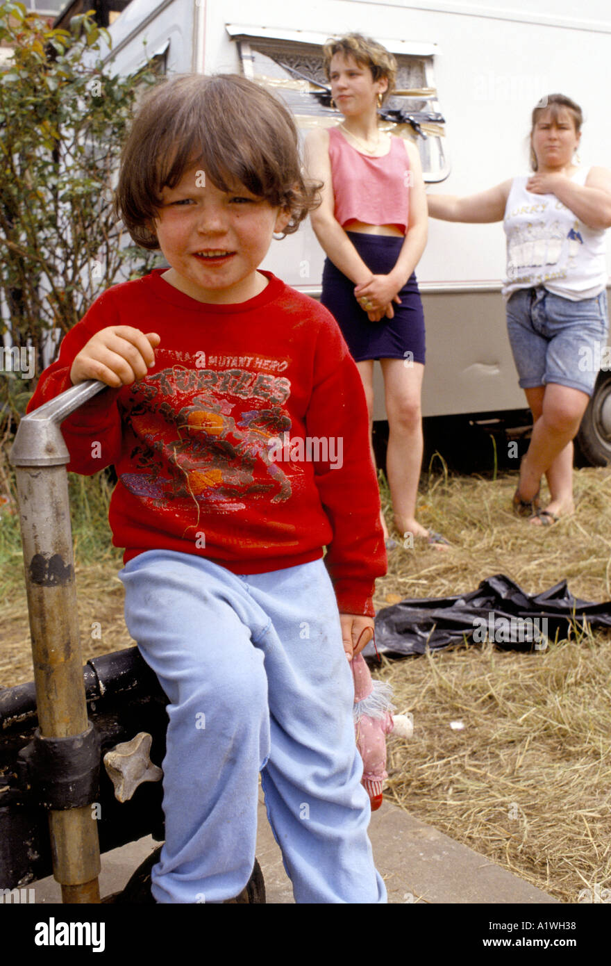 A YOUNG CHILD FROM A TRAVELLER FAMILY IN HACKNEY WITH YOUNG WOMEN STANDING NEXT TO A CARAVAN Stock Photo