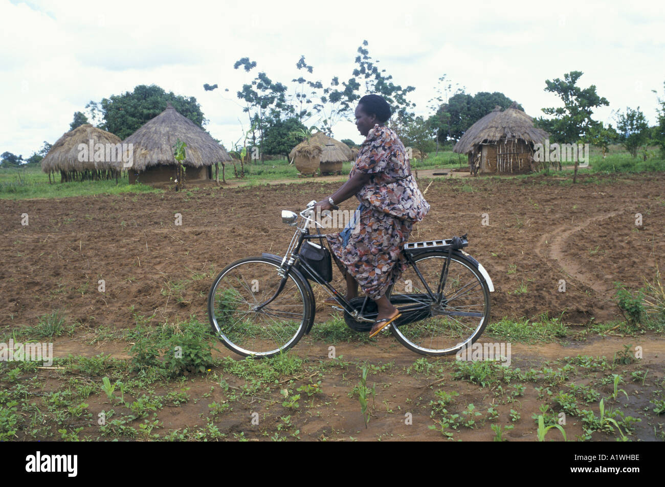 AN AIDS COUNSELLOR ON A BICYCLE VISITING A SUFFERER IN THE LOCAL COMMUNITY UGANDA 1997 Stock Photo