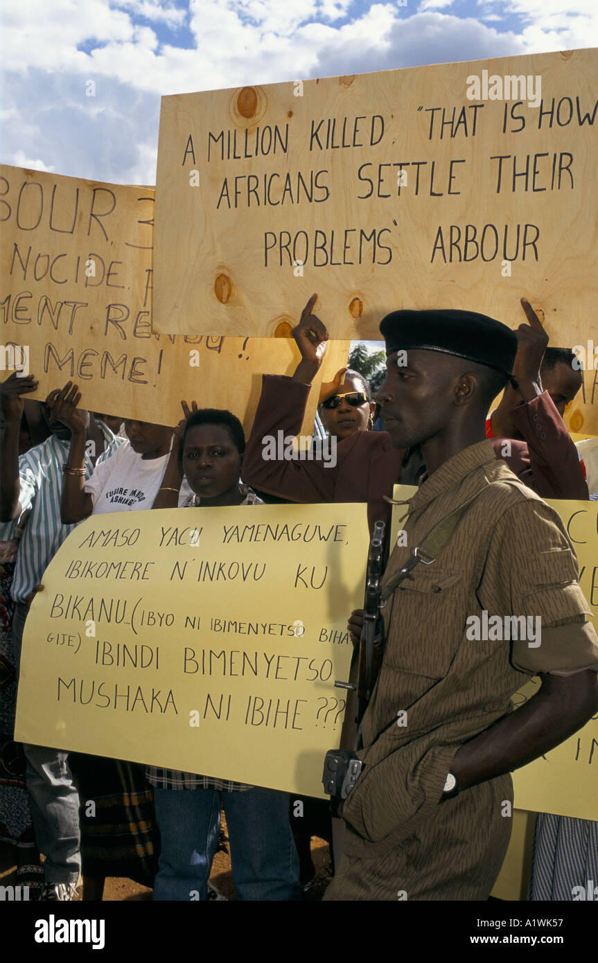 PROTEST AGAINST INTERNATIONAL TRIBUNAL AND LOUISE ARBOUR.  SOLDIER WITH GUN STANDING IN FRONT OF PEOPLE HOLDING PLACARDS Stock Photo