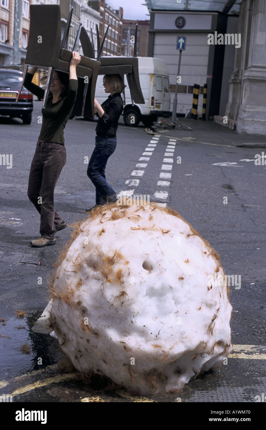 Snowballs in midsummer Andy Goldsworthy installation. Giant snowball with hair and two women passing with chairs on their heads Stock Photo