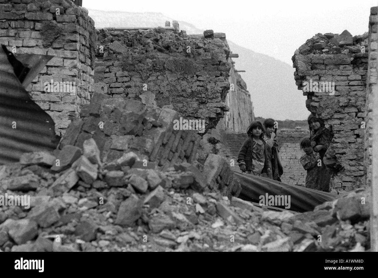 Jordi Maywan Kabul Afghanistan 1996 Black and white photo of children,three girls,  standing in ruins . Stock Photo