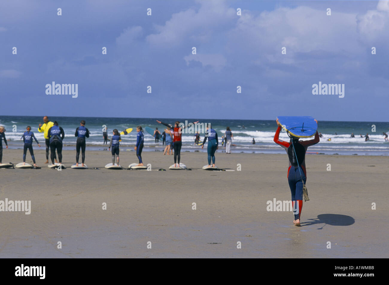 Learner surfers stand on the beach with their boards. SURF SCHOOL. POLZEATH CORNWALL UK 2001 Stock Photo