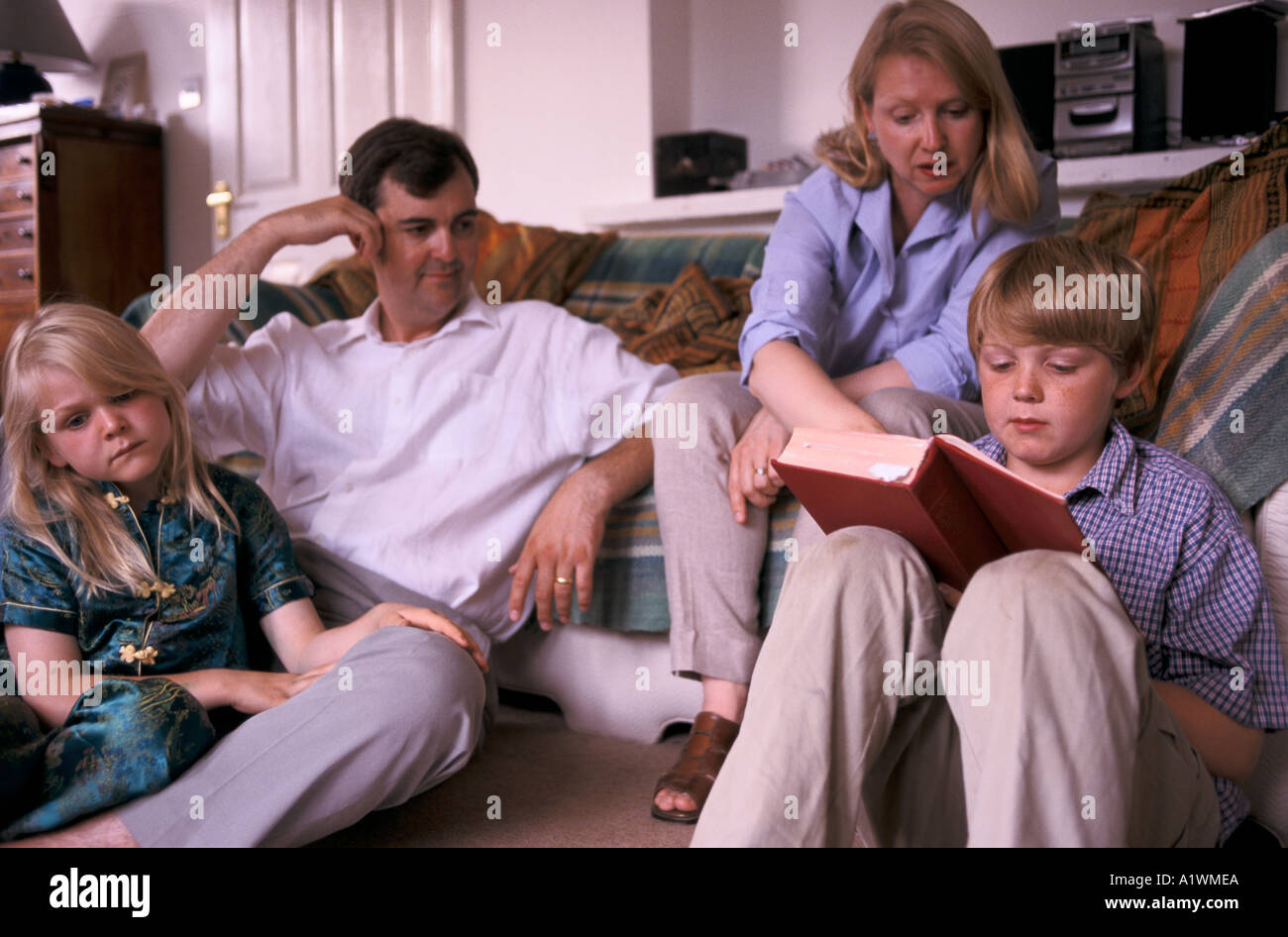 FAMILY AT HOME READING CHRISITIAN PRAYERS Stock Photo