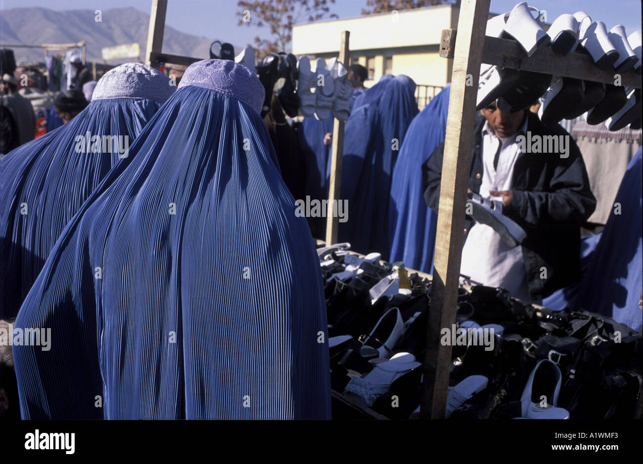 Afghan women wearing burqas shopping at Lycee Maryam Market, inspecting shoes on a stall Stock Photo