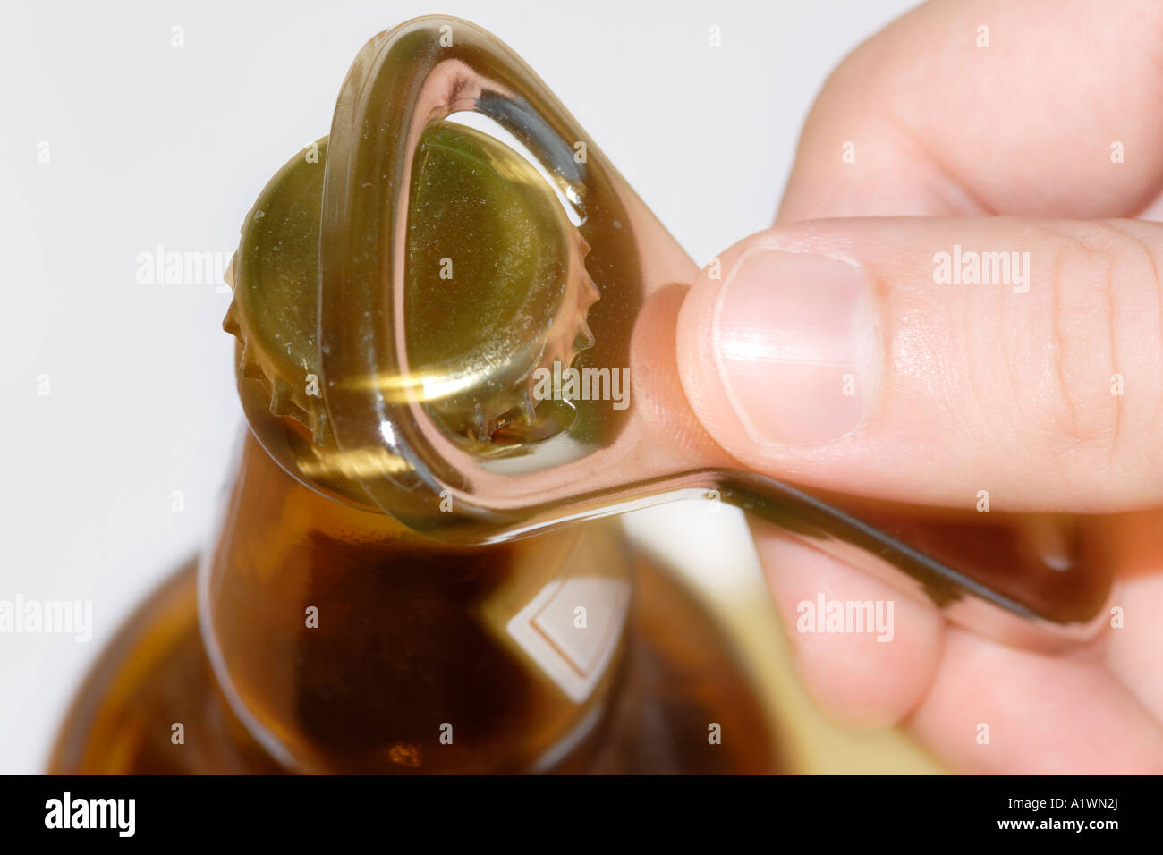 Person Opening bottle of beer with opener Stock Photo
