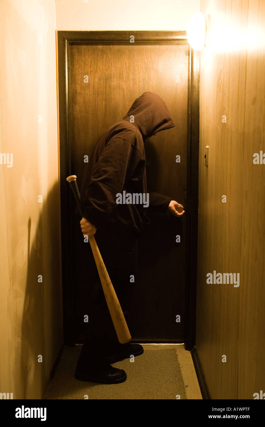 A hooded figure with a baseball bat stands at a doorway Stock Photo - Alamy