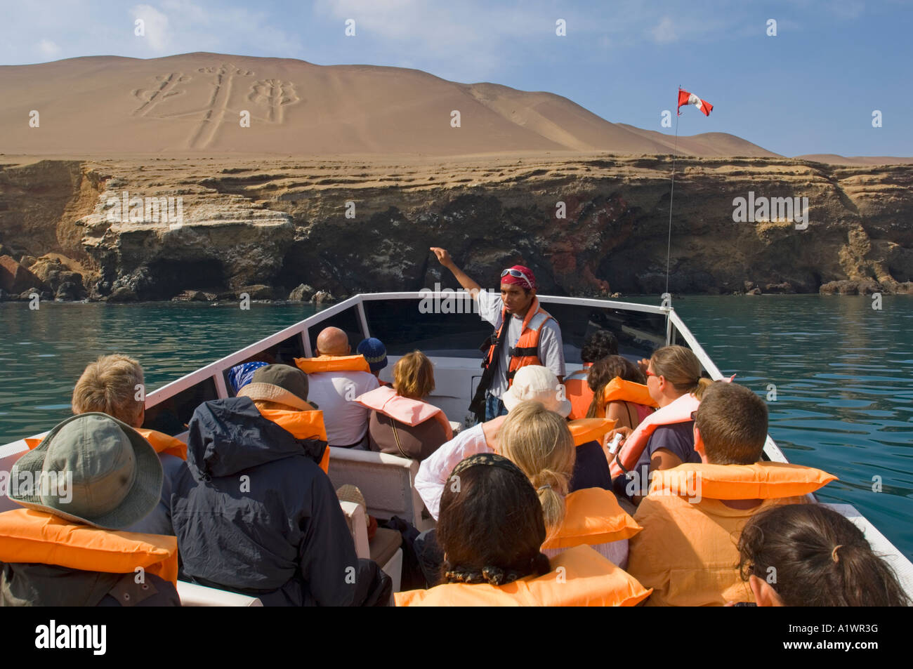 Tourists on their way out to visit the Ballestas Islands in the Paracas National Reserve, Peru, stop at the 'Candelabra'. Stock Photo
