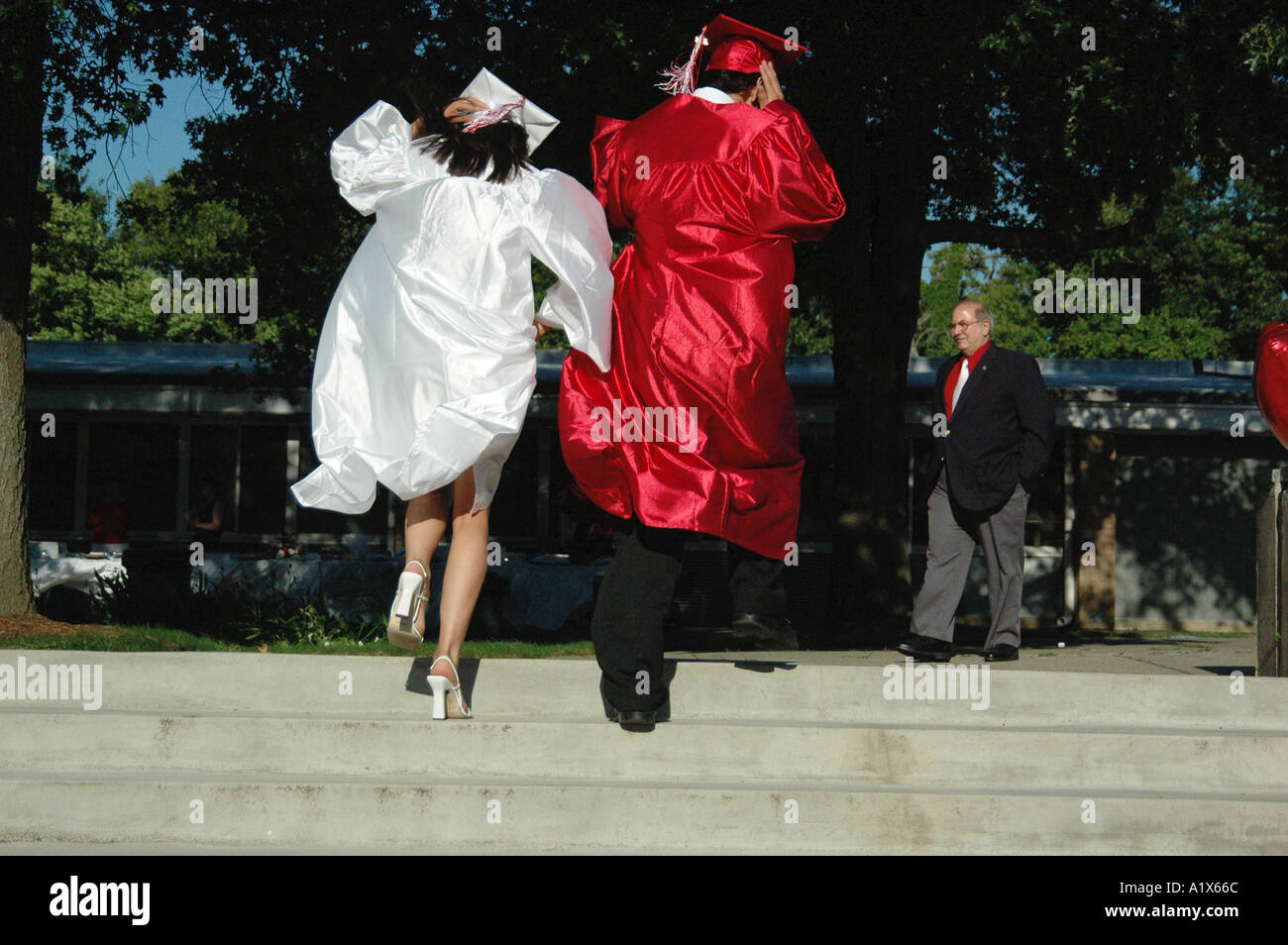two high school graduate graduates late running for graduation ceremonies up steps Stock Photo