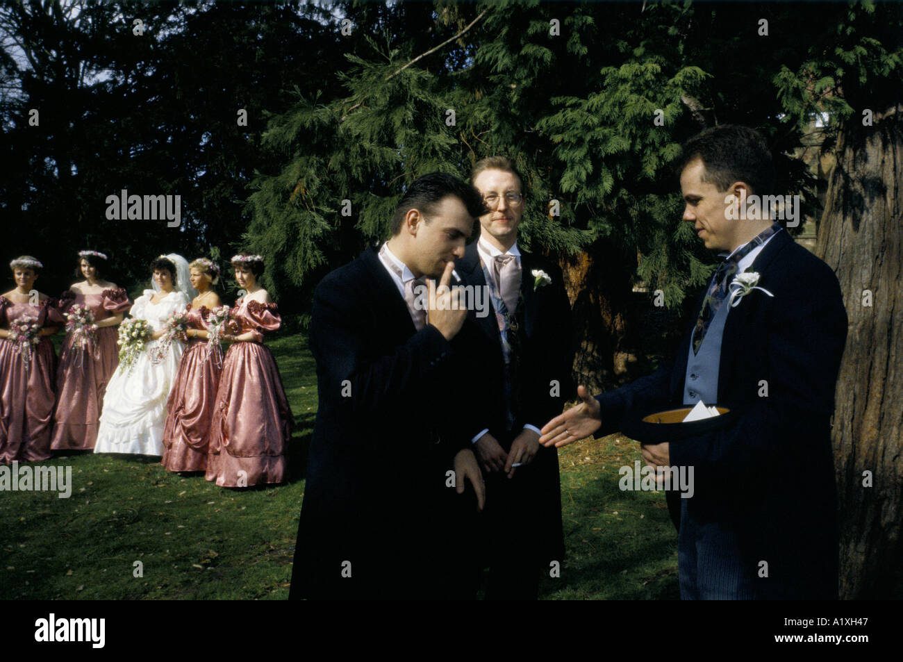 GROOM RECIEVING CONGRATULATIONS FROM BEST MAN FRIEND AS BRIDE POSES