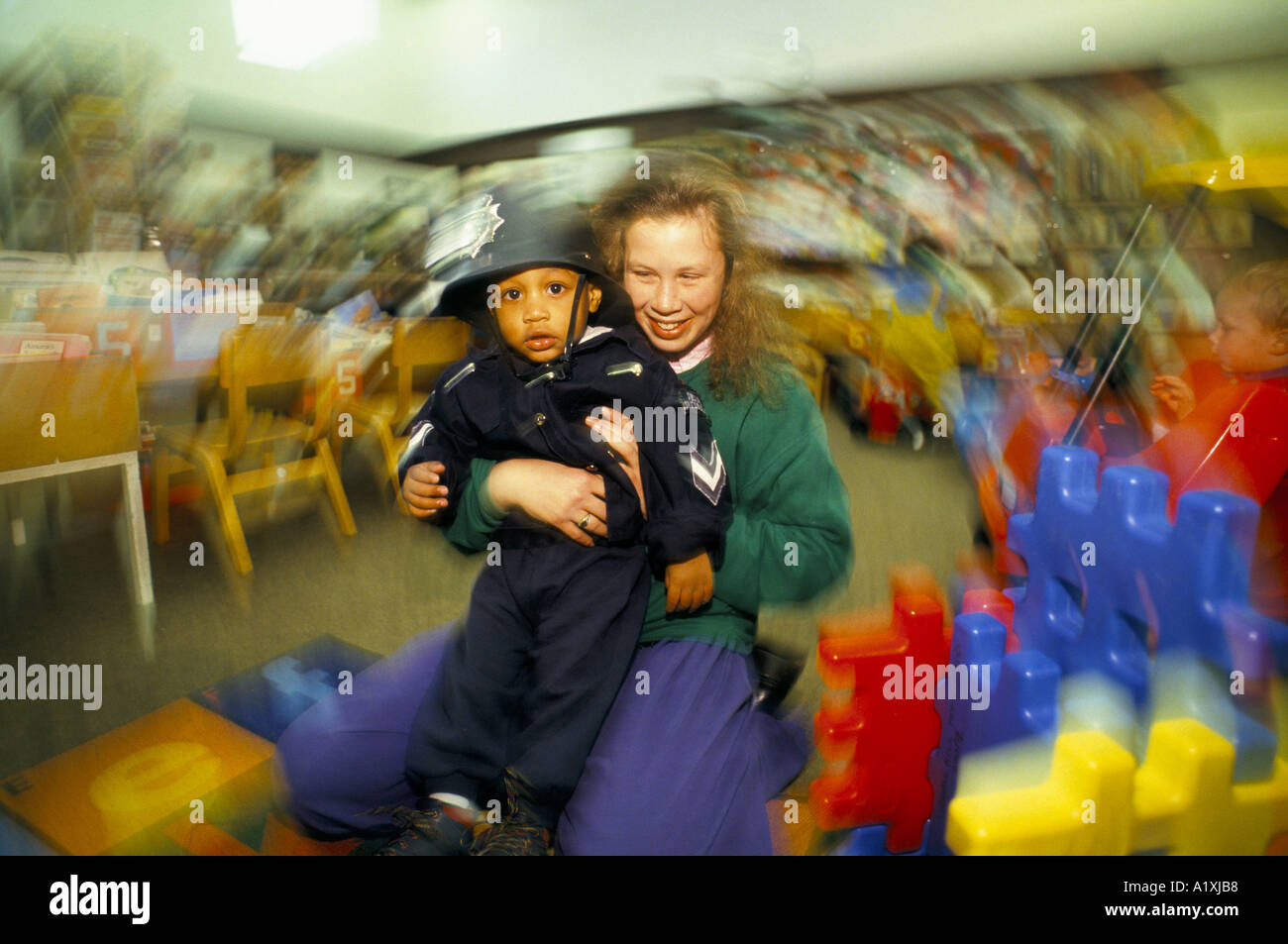 WOMAN HOLDING CHILD DRESSED IN TOY POLICEMANS UNIFORM TOY LIBRARY HARINGEY LONDON 1993 1993 Stock Photo