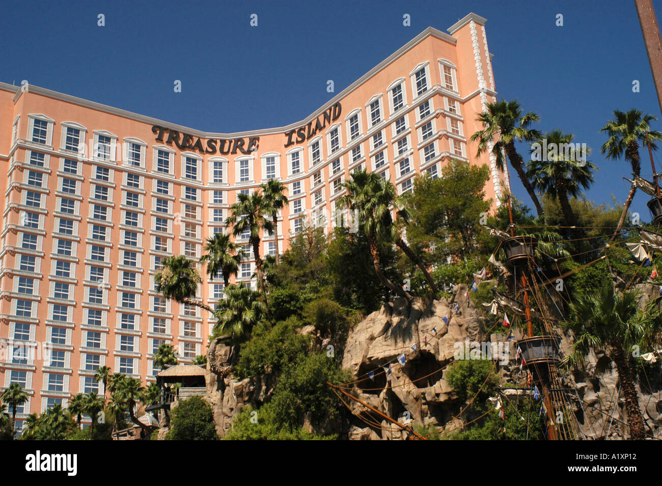 Curved pink Treasure Island Hotel and Casino palm trees and galleon ship outside it Las Vegas Boulevard The Strip Stock Photo