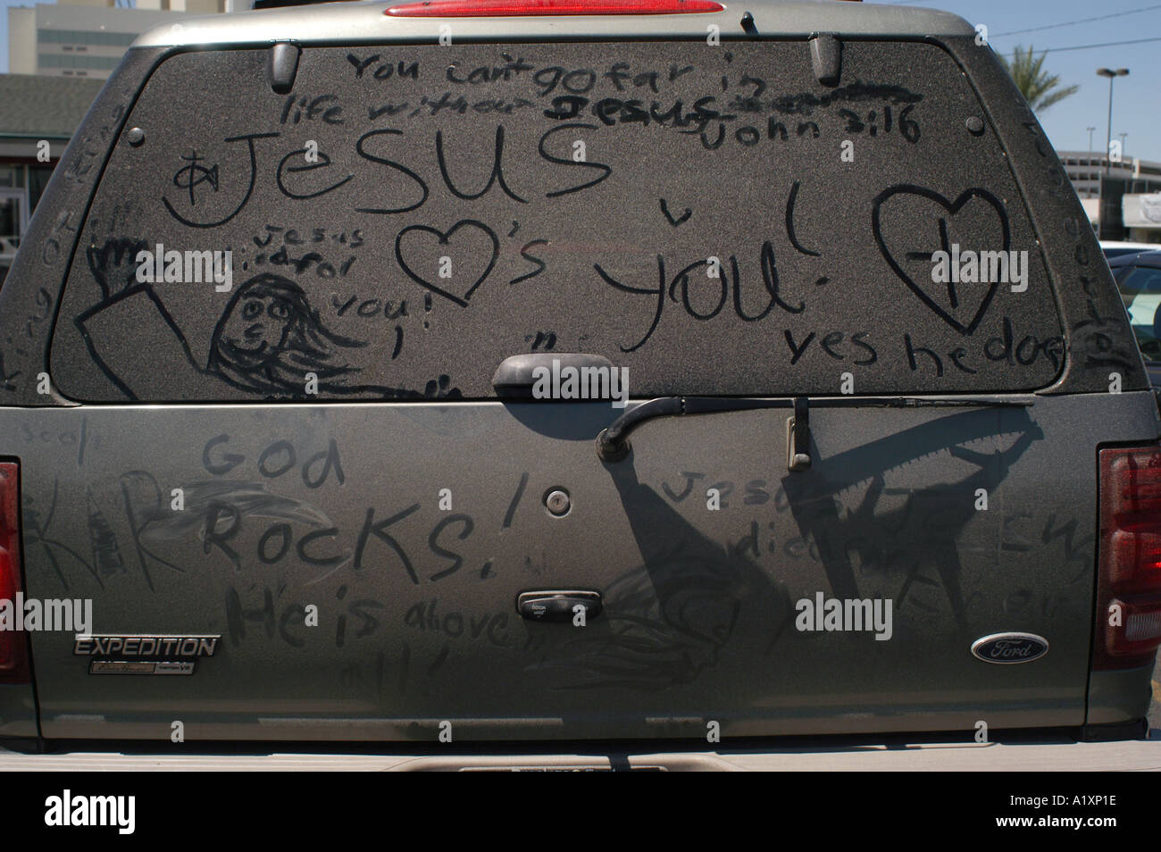 Religous graffitti finger painted in dirt on the rea window of an American car Stock Photo