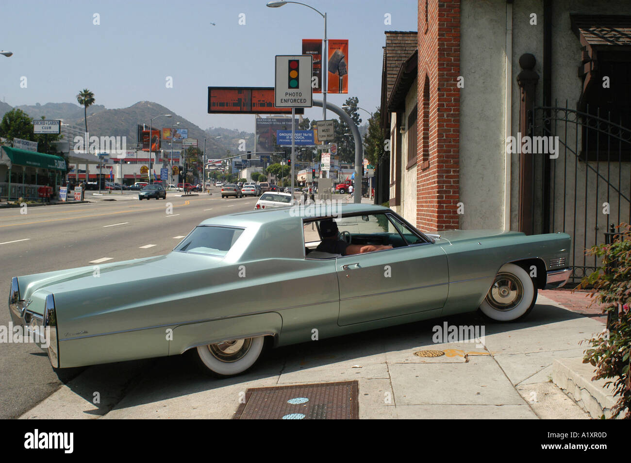 Large American Cadillac esque car from the 1970 s parked across the pavement next to a busy road in Hollywood Stock Photo