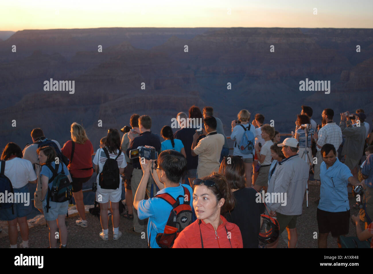 At sunset tourists crowd together at a view point to lookout over the Grand Canyon from the South Rim Stock Photo