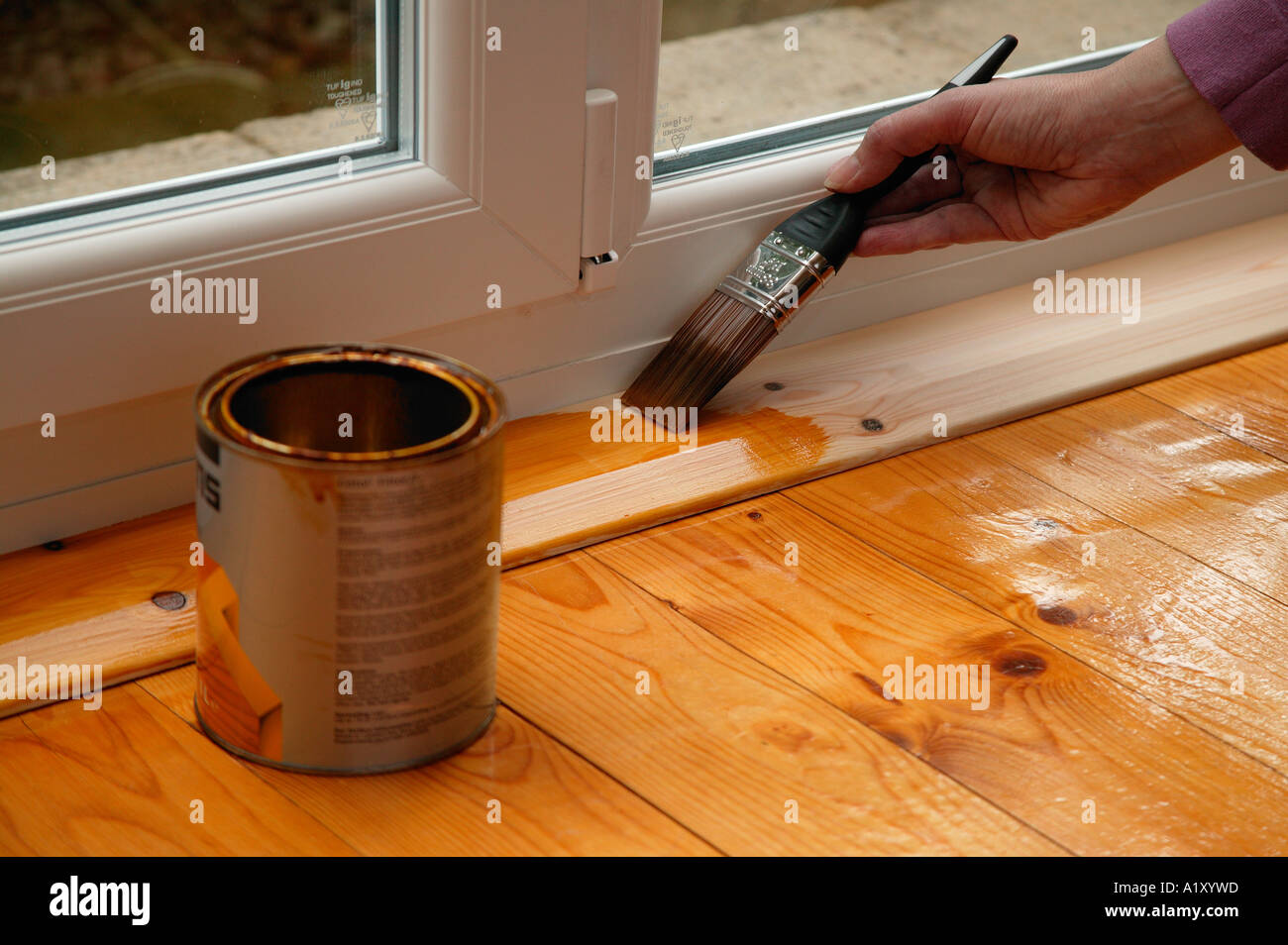 Varnishing the wooden surround of  a pvc door with a varnish brush and tin of varnish Stock Photo