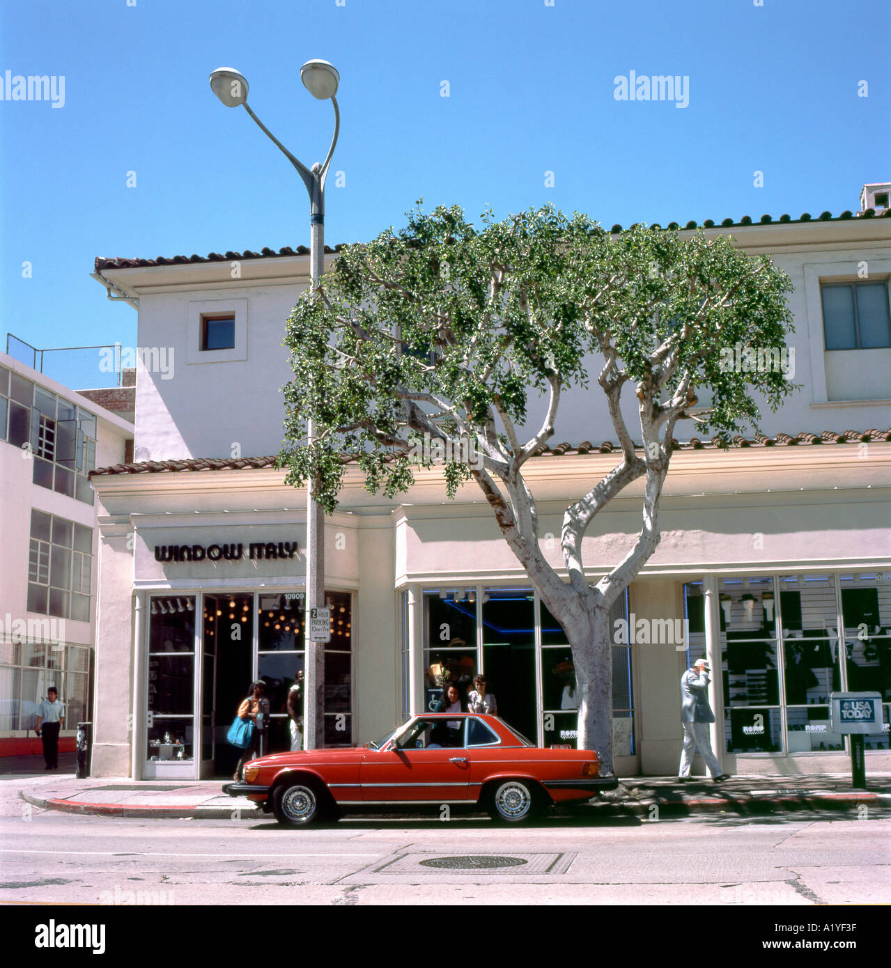 Red car parked outside shops in a Westwood Village street scene in 1989