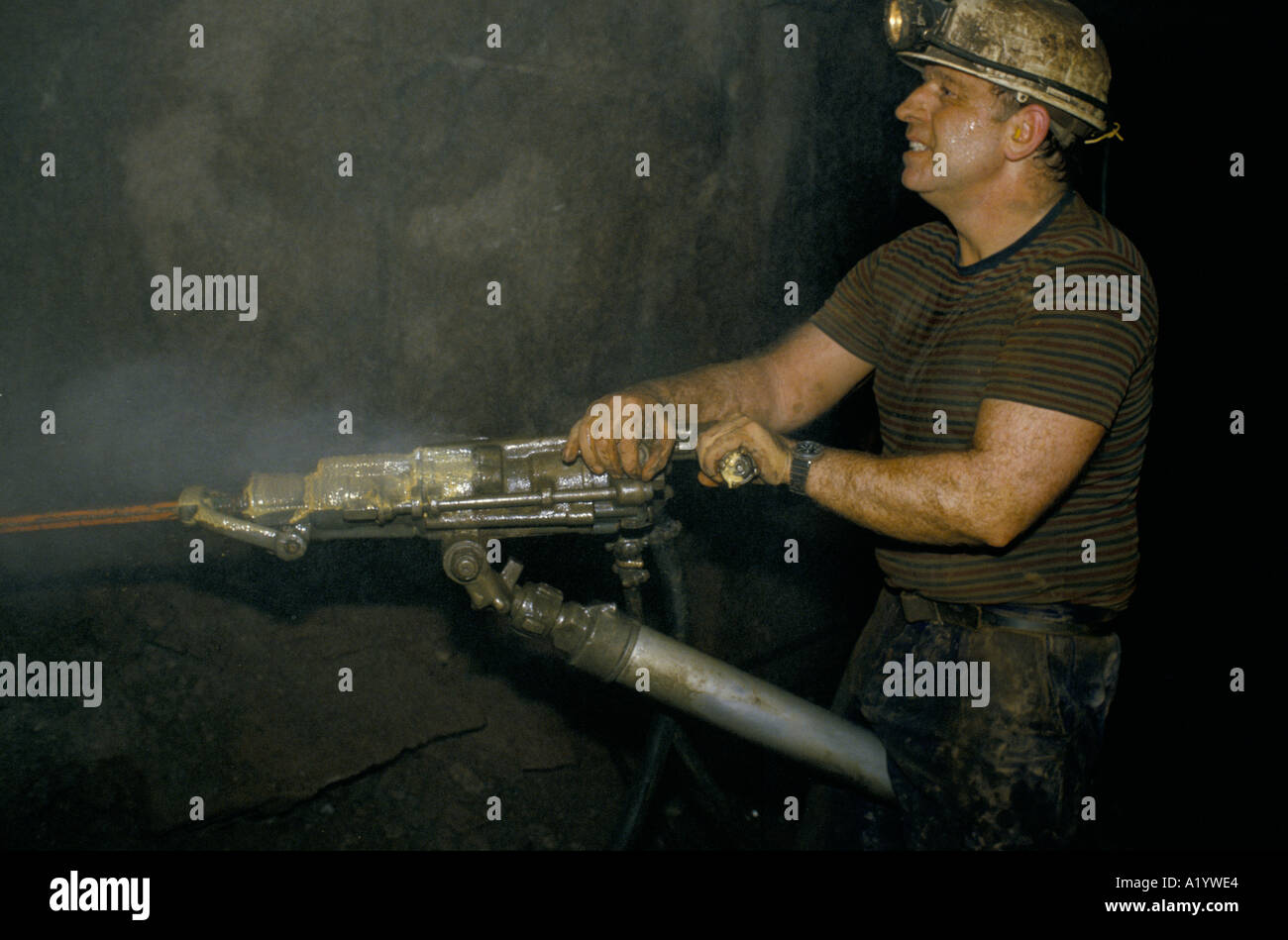 MINER WITH HELMET HEADTORCH AT WORK WITH MACHINERY IN GEEVOR TIN MINE CORNWALL Stock Photo