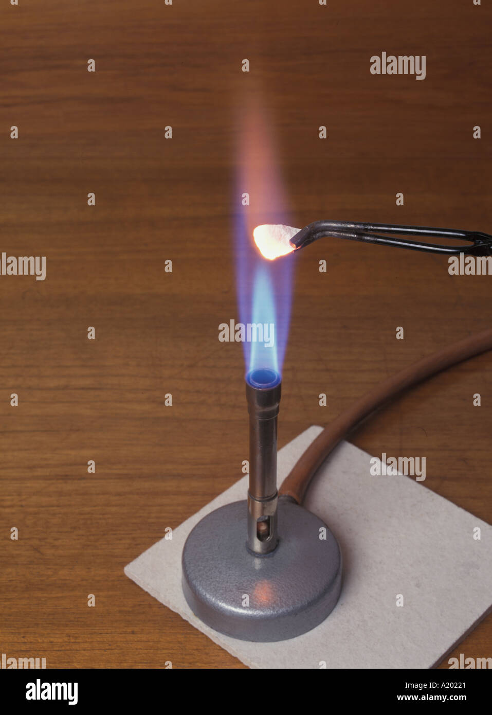 A piece of white marble being heated with a Bunsen burner producing a blue flame on a heatproof