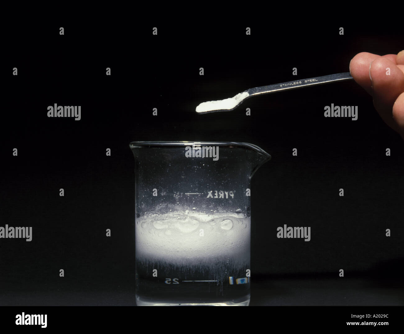 calcium carbonate on spatula above fizzing beaker containing dilute