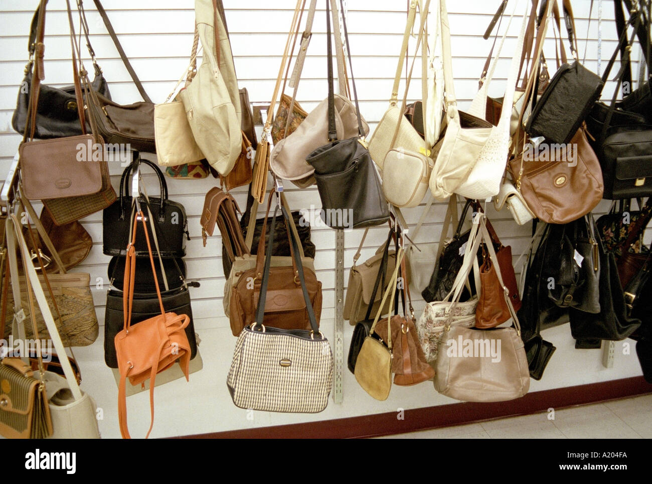 Purses hanging from wall in thrift store Stock Photo